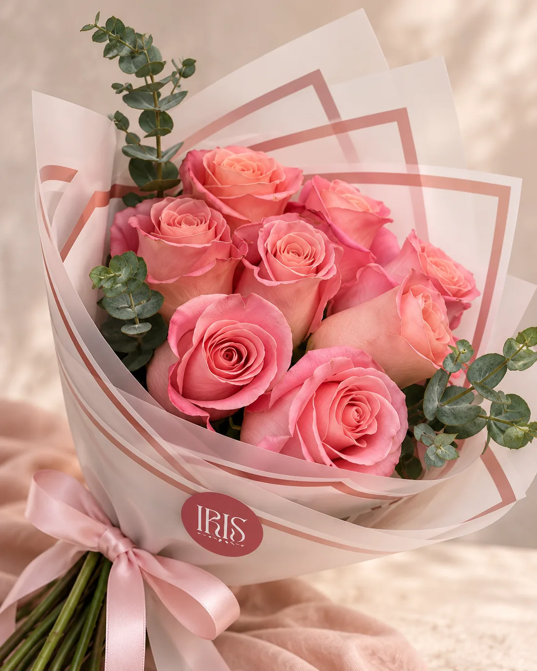Ramo de rosas rosadas con eucalipto, envoltura clara y lazo rosa